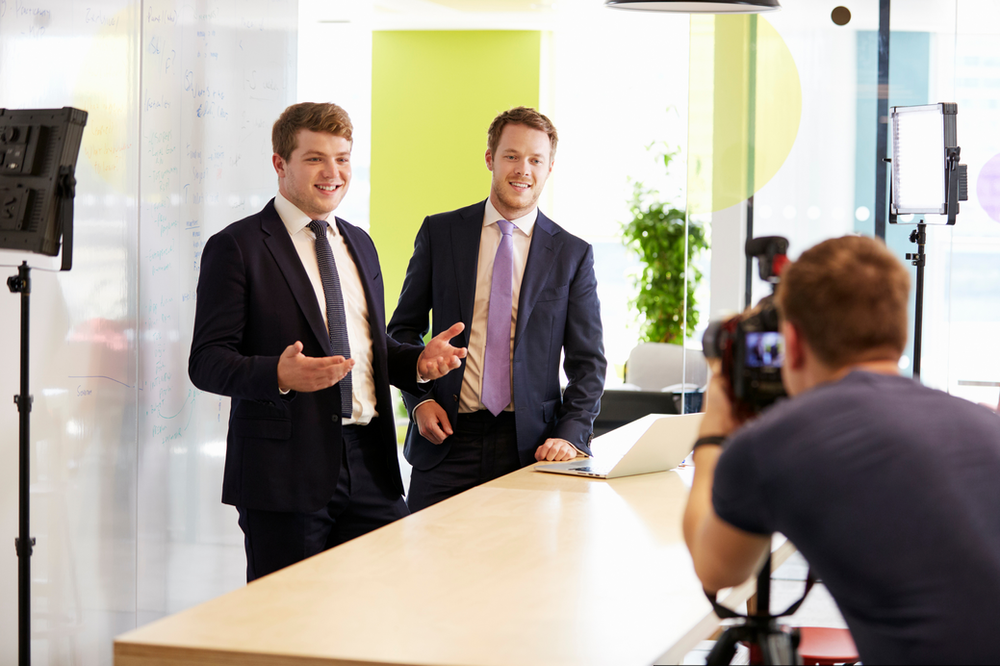 A man is taking a picture of two men in suits and ties.