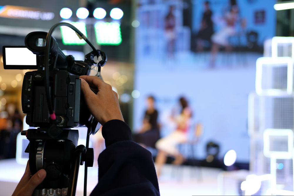 A person is holding a video camera in front of a group of people.