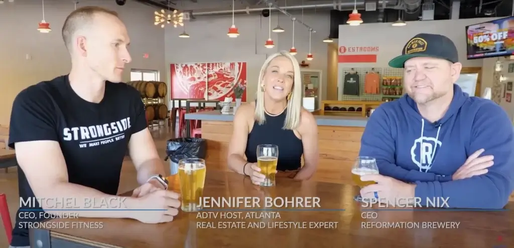 A man and a woman are sitting at a table holding beer glasses.