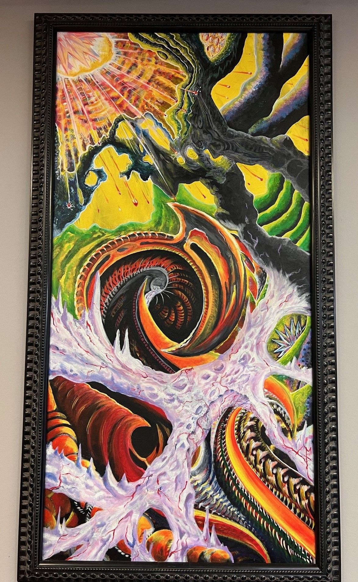 A colorful painting in a black frame is hanging on a wall.