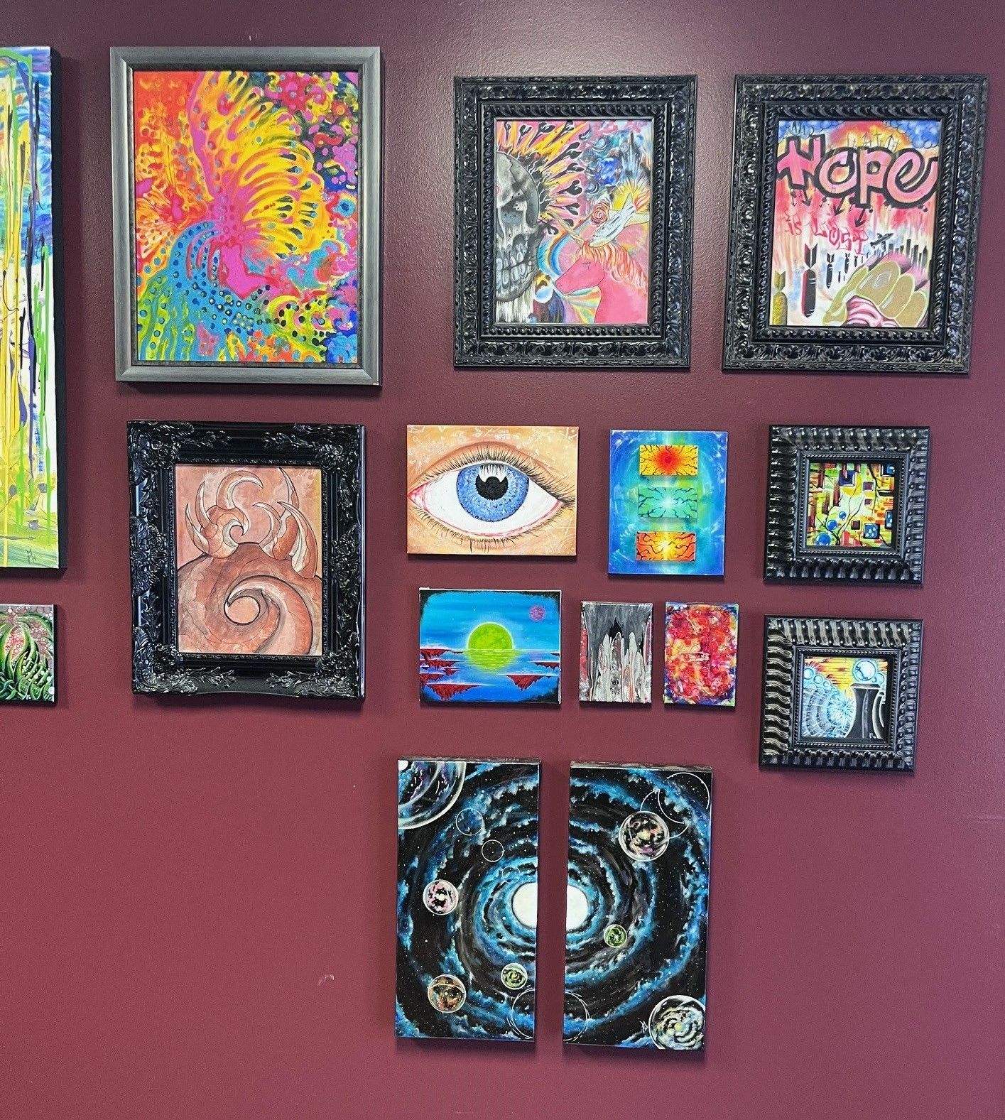 A collage of paintings on a wall with one that says happy