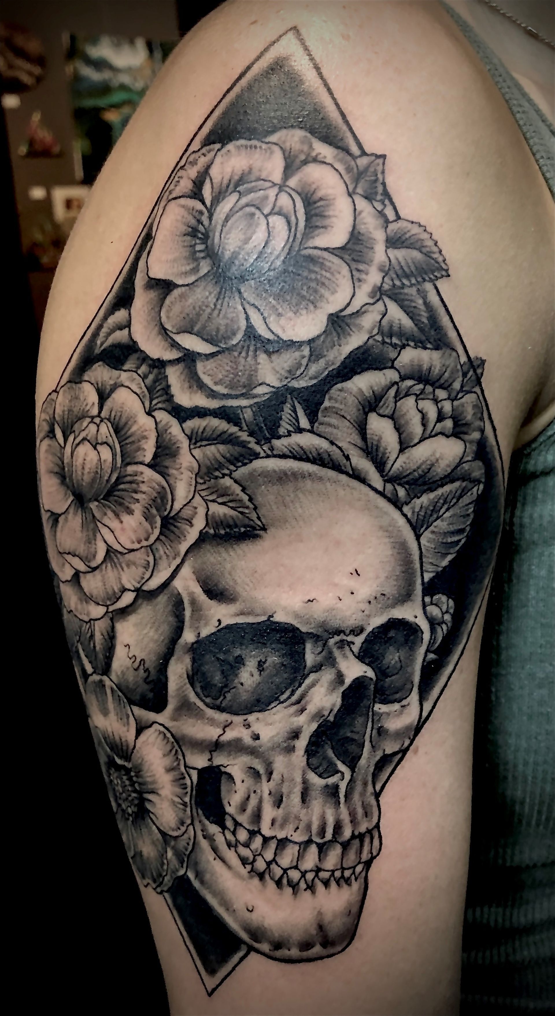A woman has a tattoo of a skull and roses on her arm.