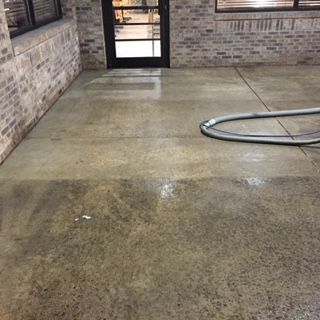 A concrete floor with a hose attached to it in a room with a brick wall.