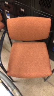 An orange chair is sitting in front of a row of lockers.