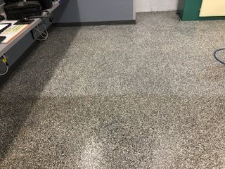 A gray carpeted floor in a room with a desk and a computer.