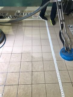 A person is cleaning a tiled floor with a vacuum cleaner.