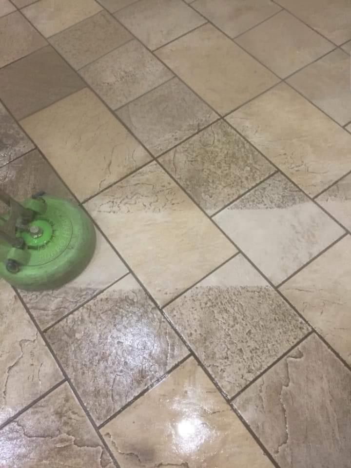 A person is cleaning a tile floor with a mop.