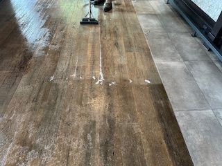 A person is cleaning a wooden floor with a vacuum cleaner.