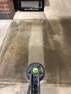 A person is cleaning a concrete floor with a machine.