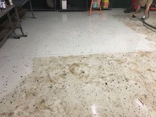 A person is cleaning a dirty floor with a vacuum cleaner.