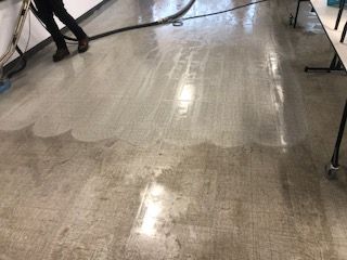 A person is cleaning a dirty floor with a vacuum cleaner.