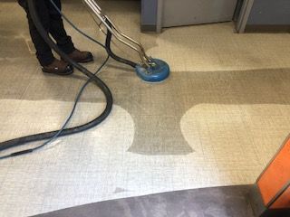 A person is using a vacuum cleaner to clean a tile floor.