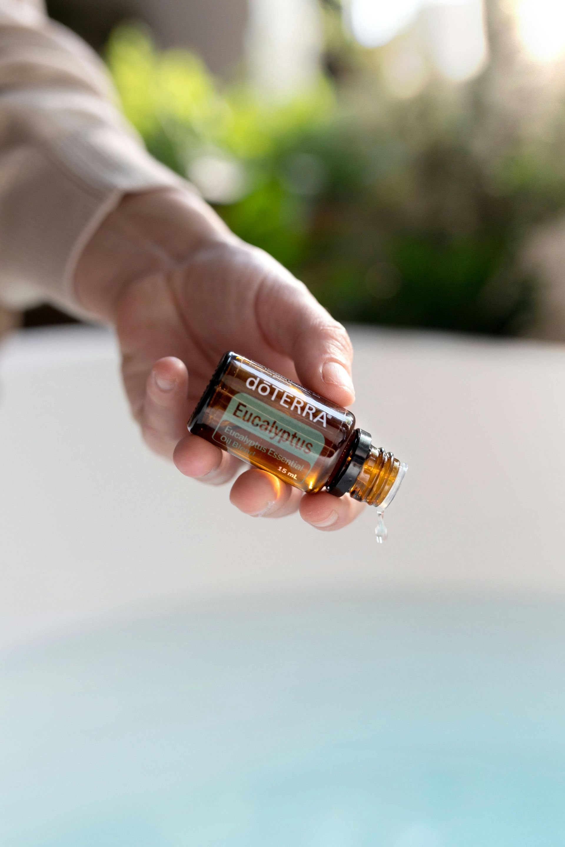 A person is holding a bottle of essential oil in their hand.