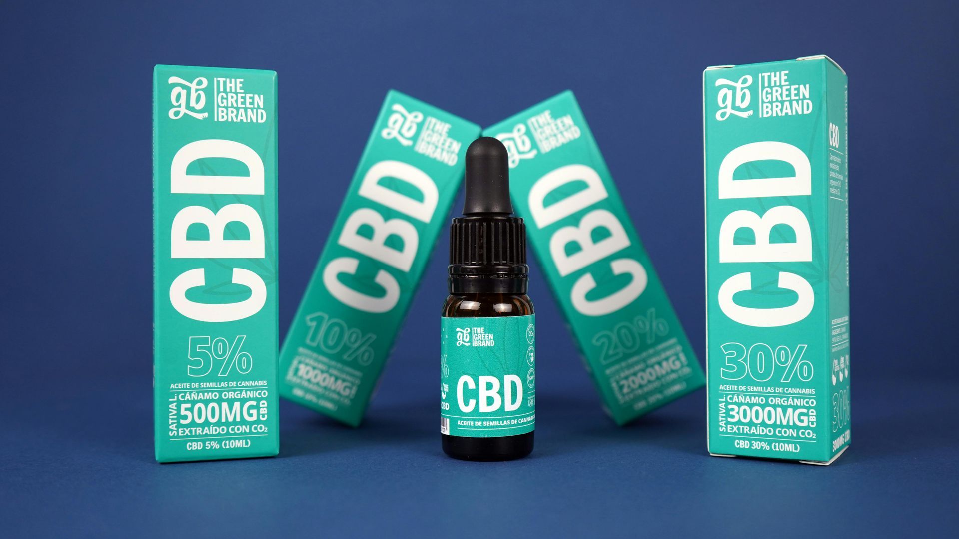 A bottle of cbd oil is surrounded by boxes on a blue surface.