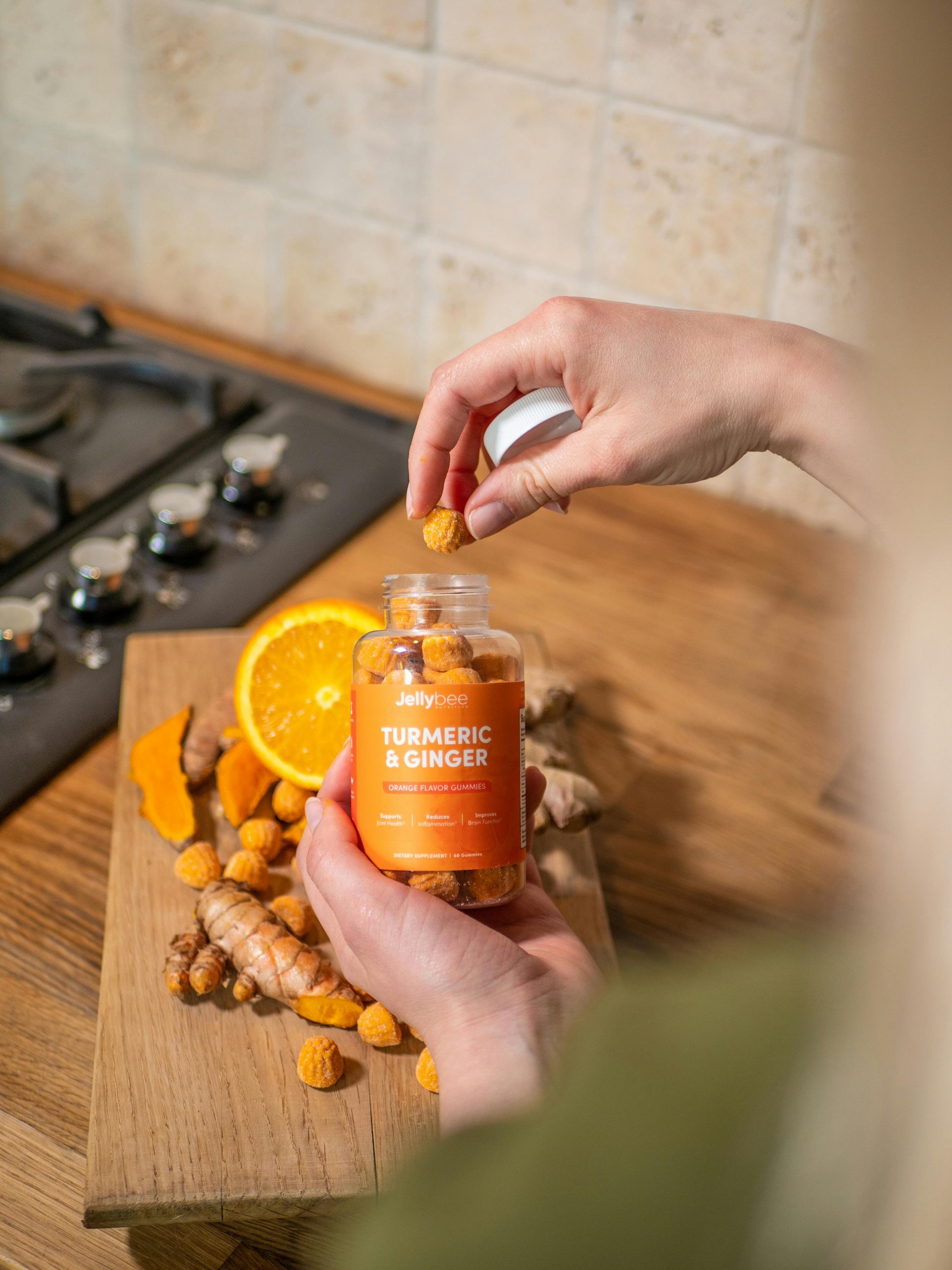 A person is holding a bottle of turmeric and ginger gummies.