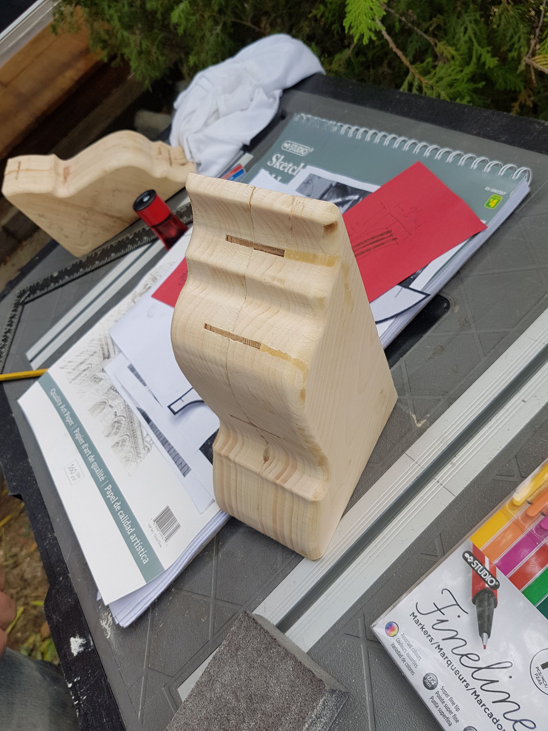 Un morceau de bois est posé sur une table à côté d'un cahier et de crayons