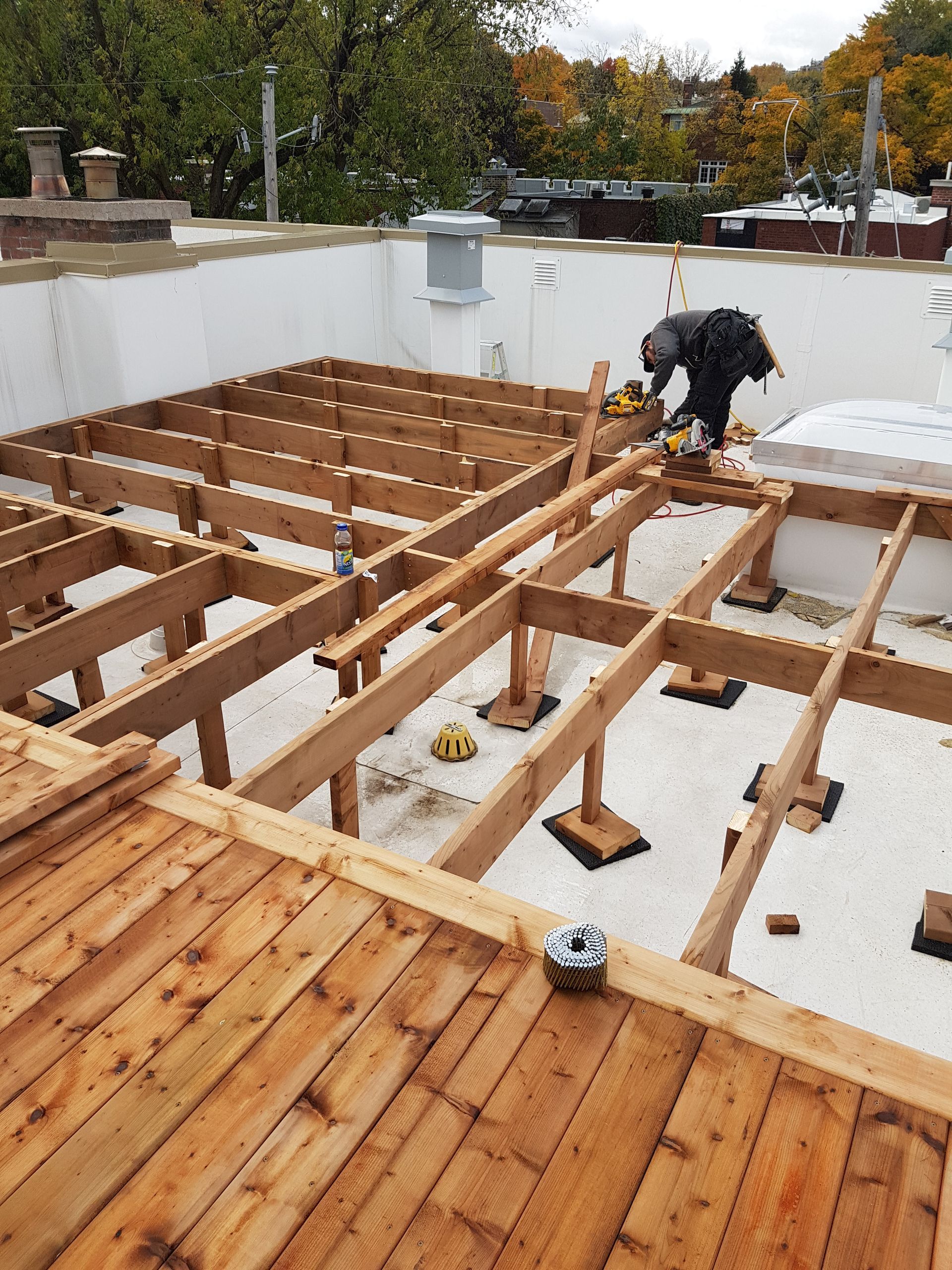 Un homme travaille sur une terrasse en bois sur un toit.