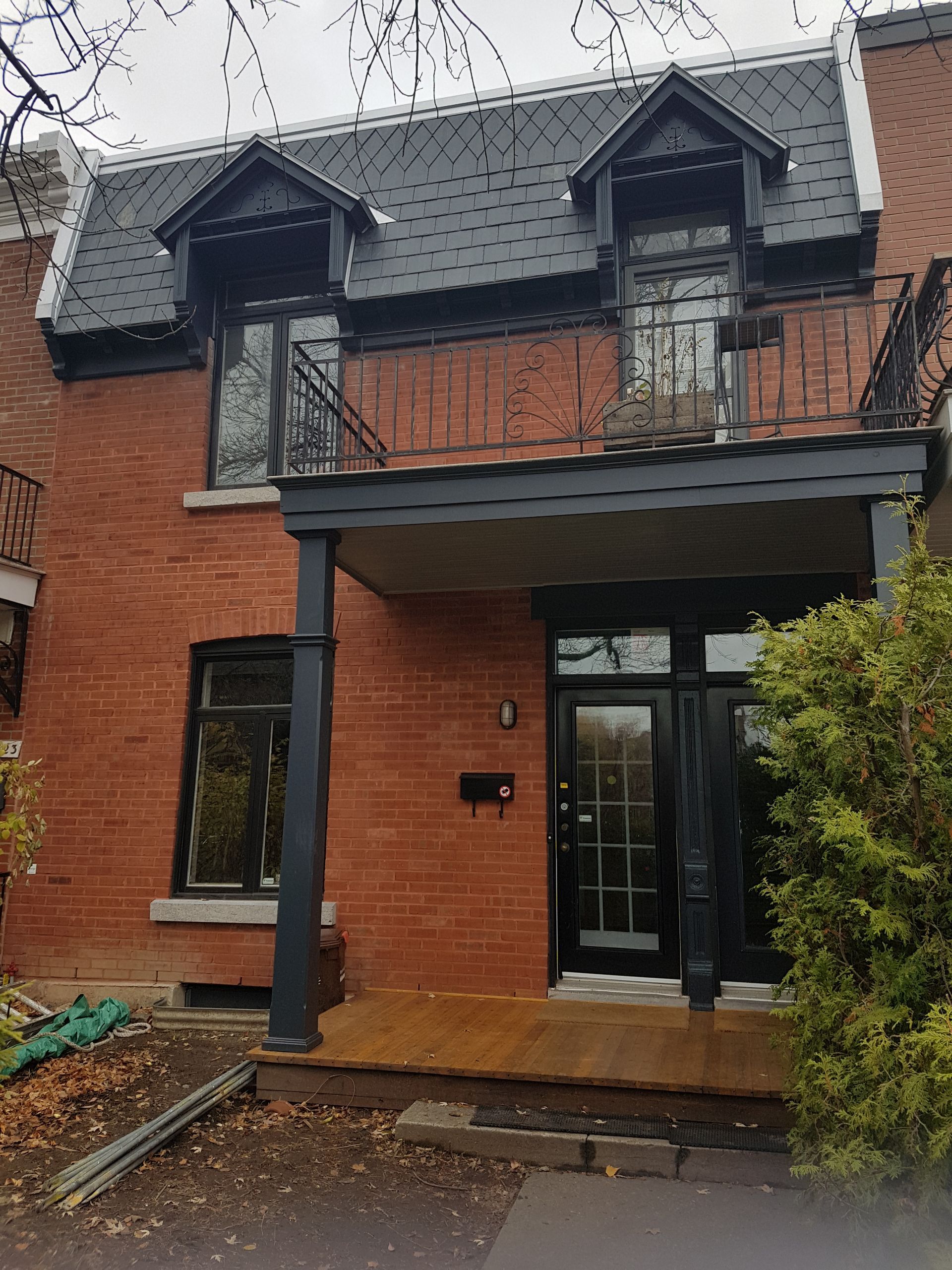 Une maison en brique avec un porche noir et un toit noir
