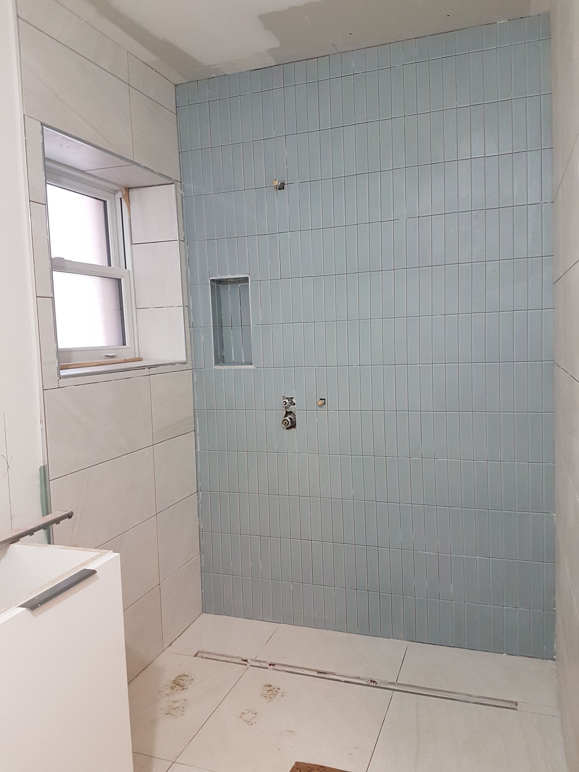 Une salle de bain avec carrelage bleu et fenêtre