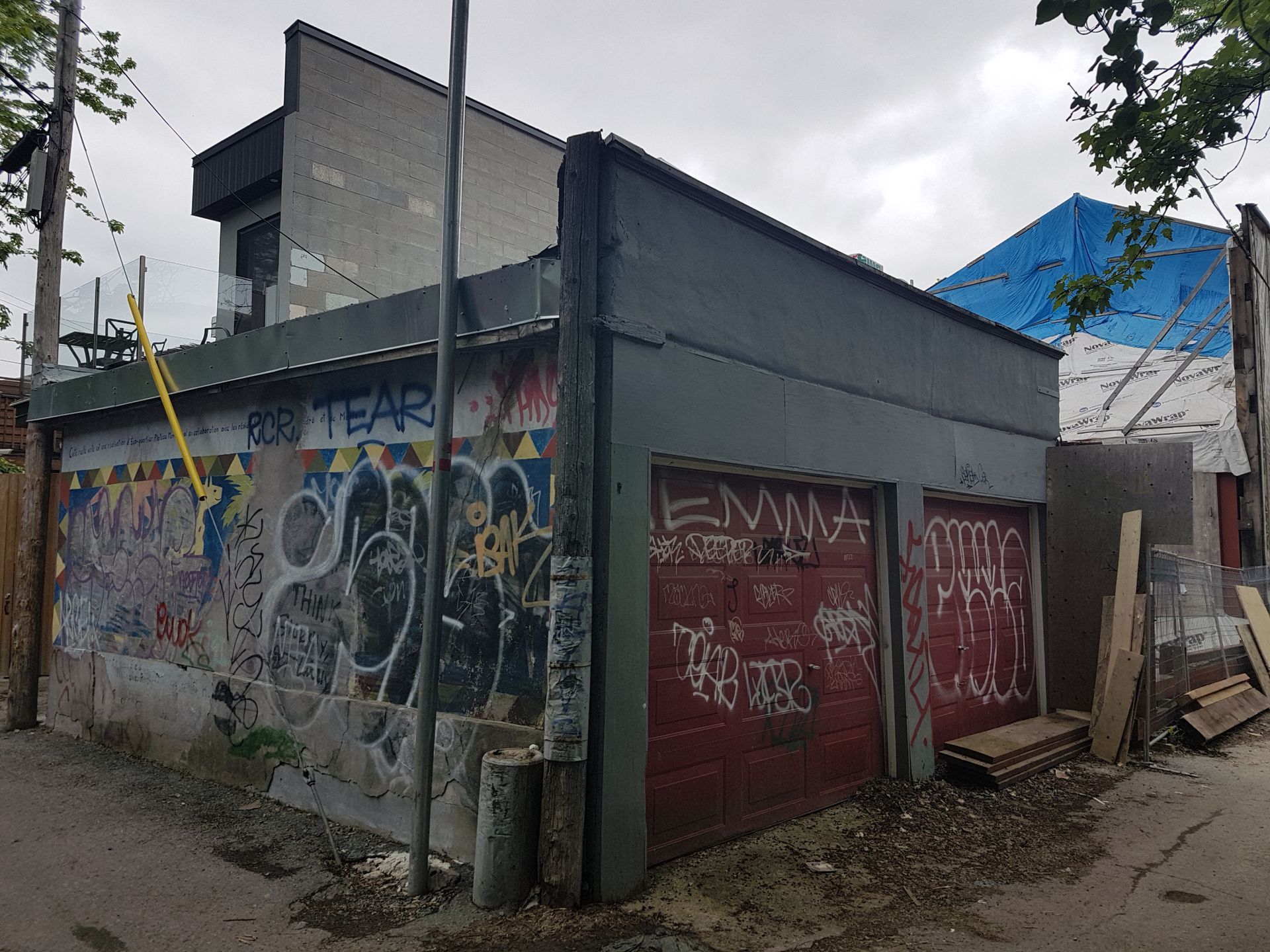 Un immeuble avec des graffitis sur le côté et une porte de garage rouge.