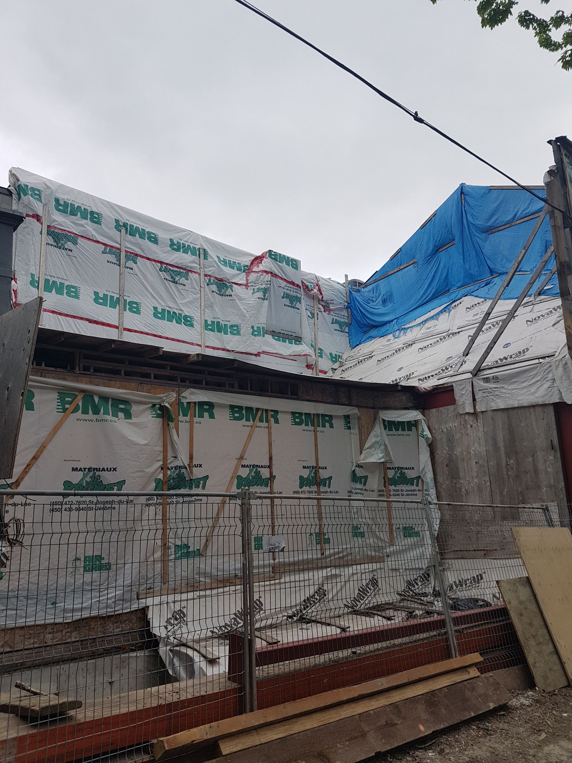 Un bâtiment en construction avec une bâche bleue dessus.