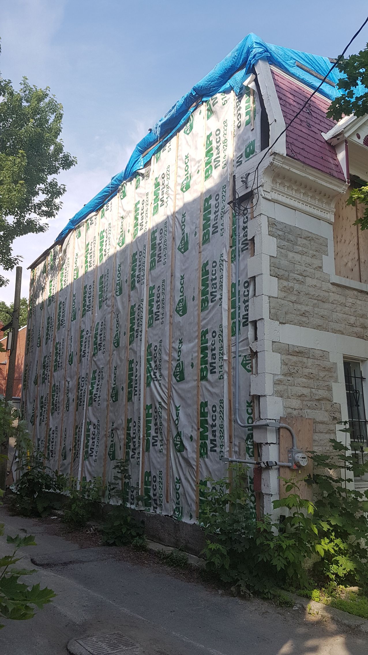 Un grand bâtiment avec une bâche bleue dessus.