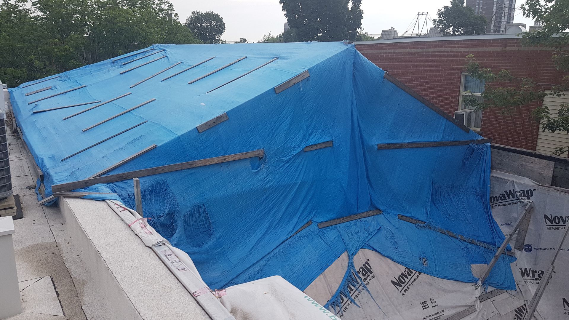 Une bâche bleue recouvre le toit d'un immeuble.