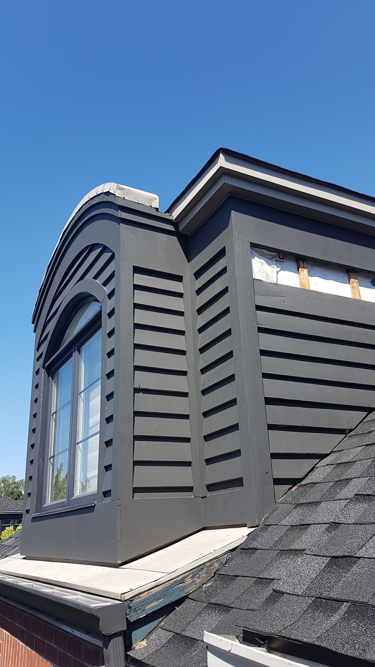 Le toit d'une maison avec une fenêtre et des volets.