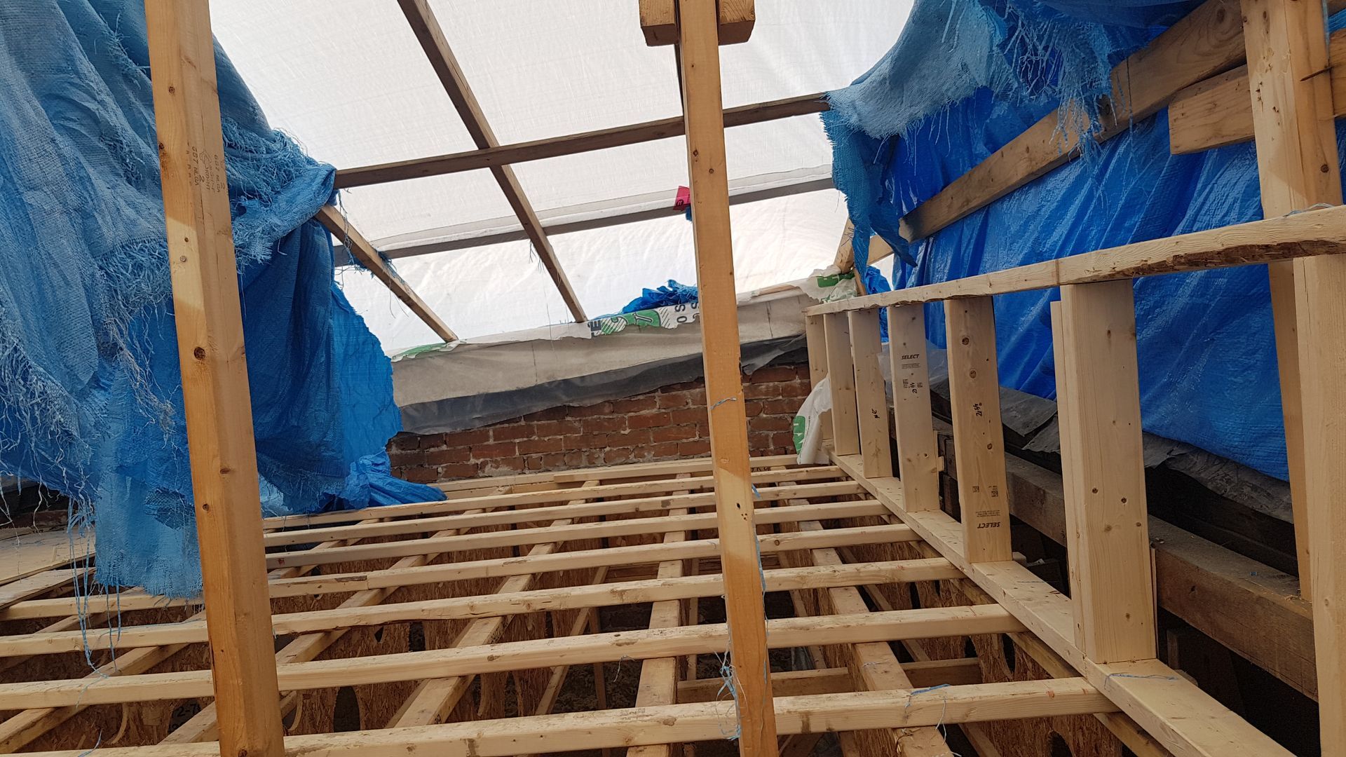 Une structure en bois avec une bâche bleue dessus.
