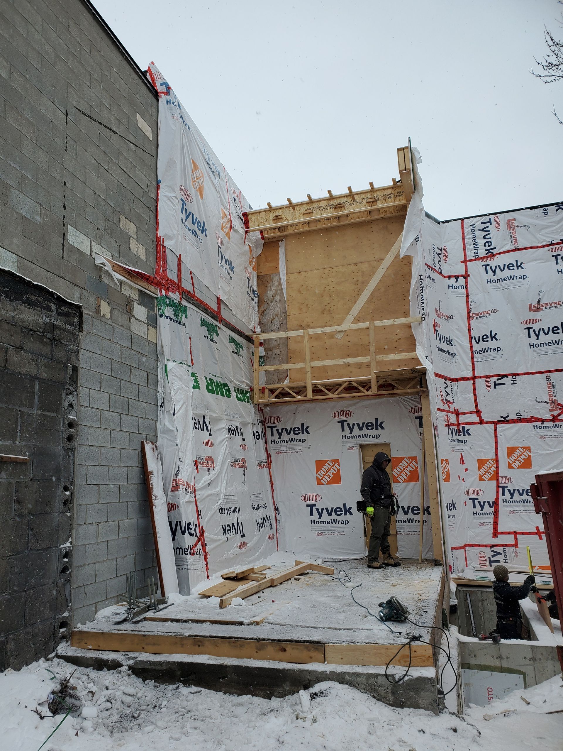 Un homme se tient devant un bâtiment en construction recouvert de polystyrène.