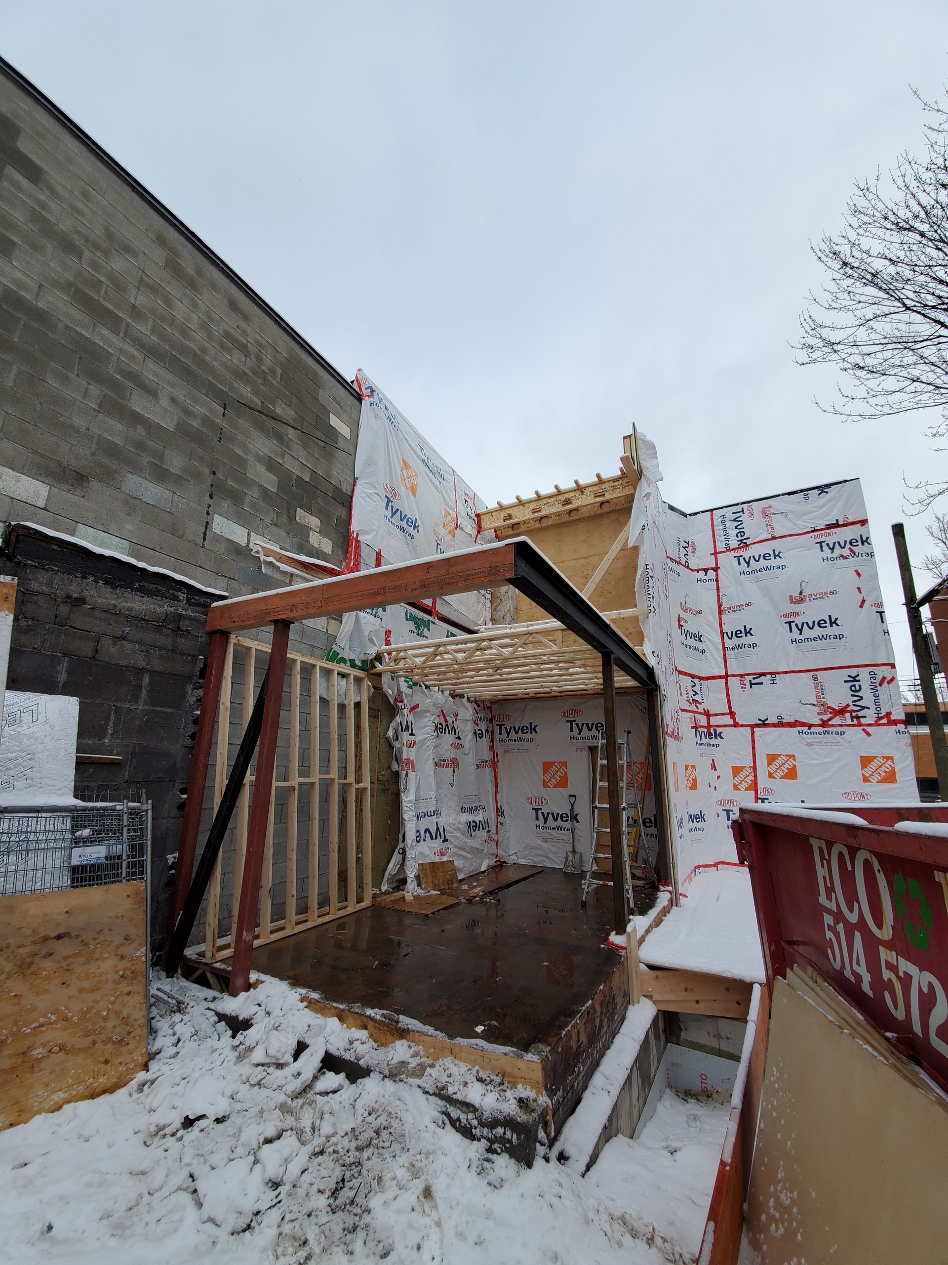 Un bâtiment est en construction dans la neige à côté d'une benne à ordures.
