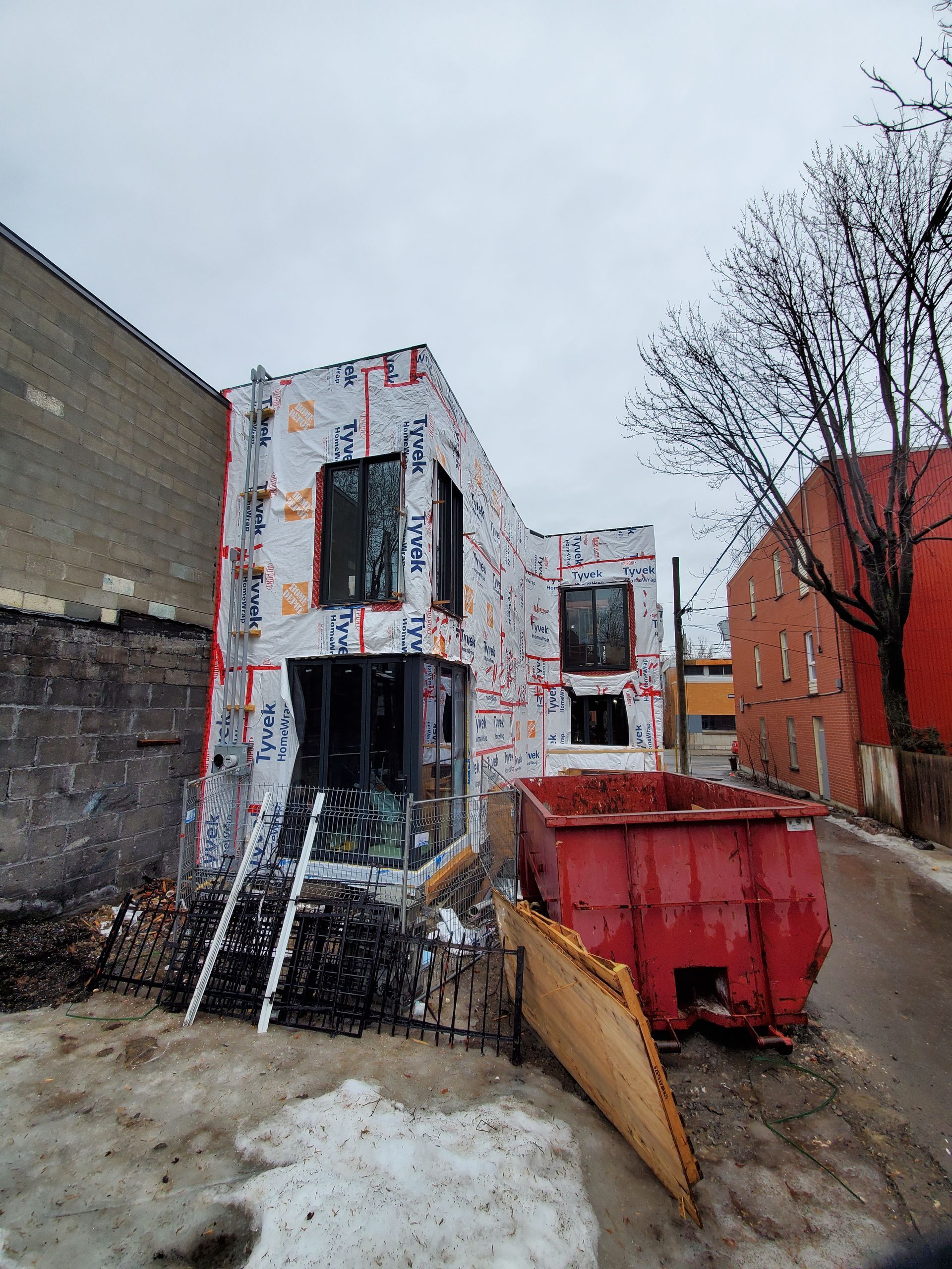 Un bâtiment en construction avec une benne rouge devant.