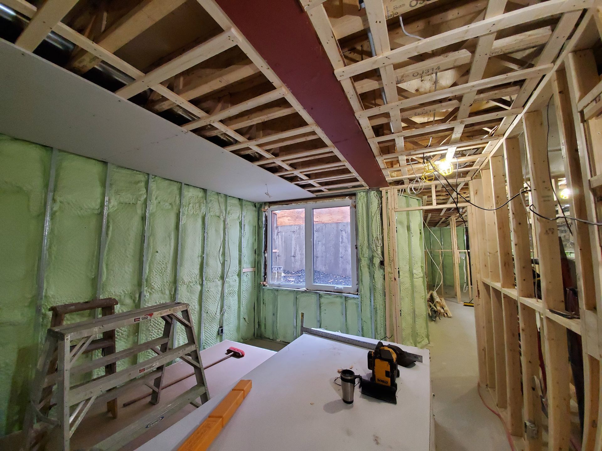 Une pièce dans une maison en construction avec une fenêtre et une échelle.