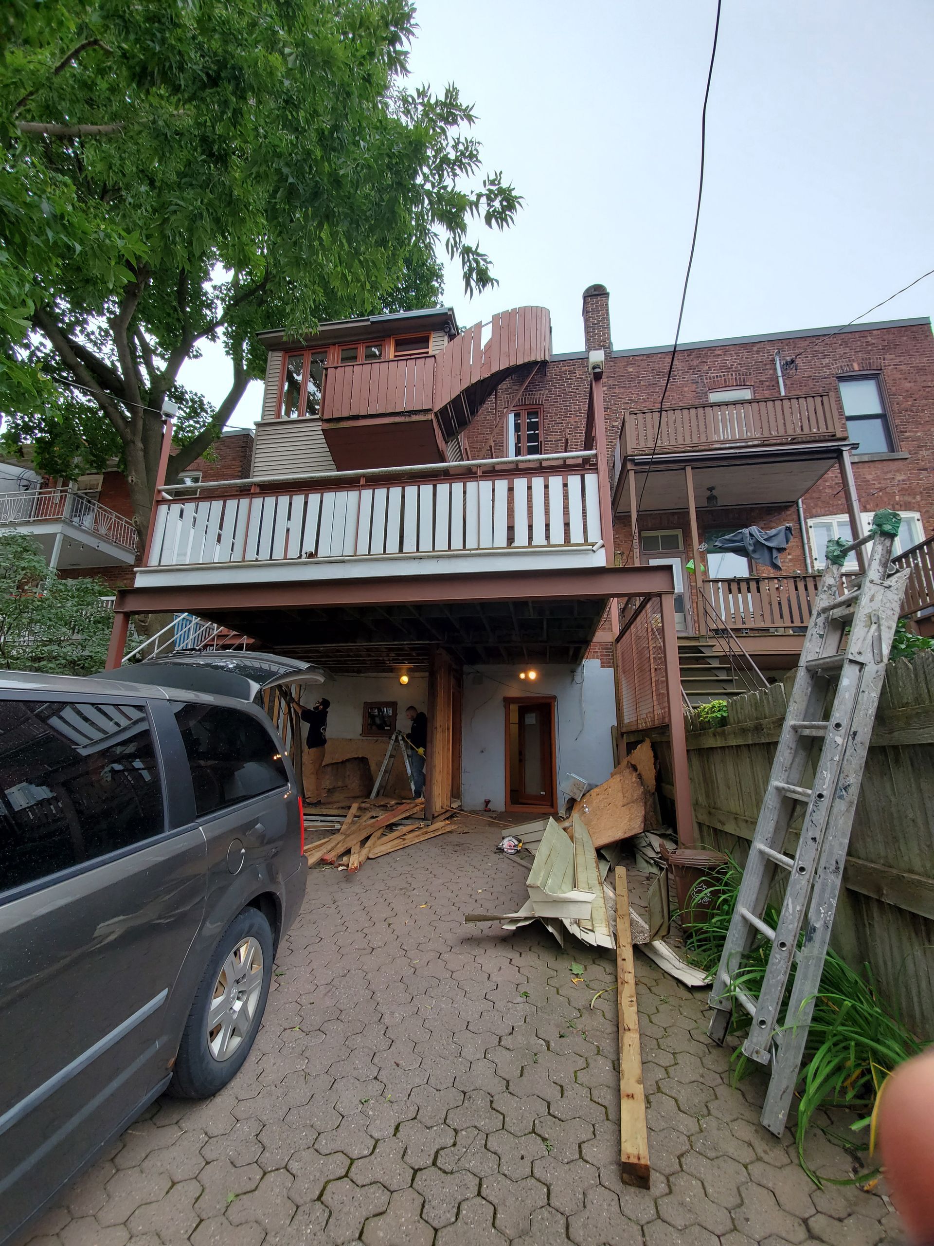 Une camionnette est garée devant un bâtiment en brique avec terrasse.