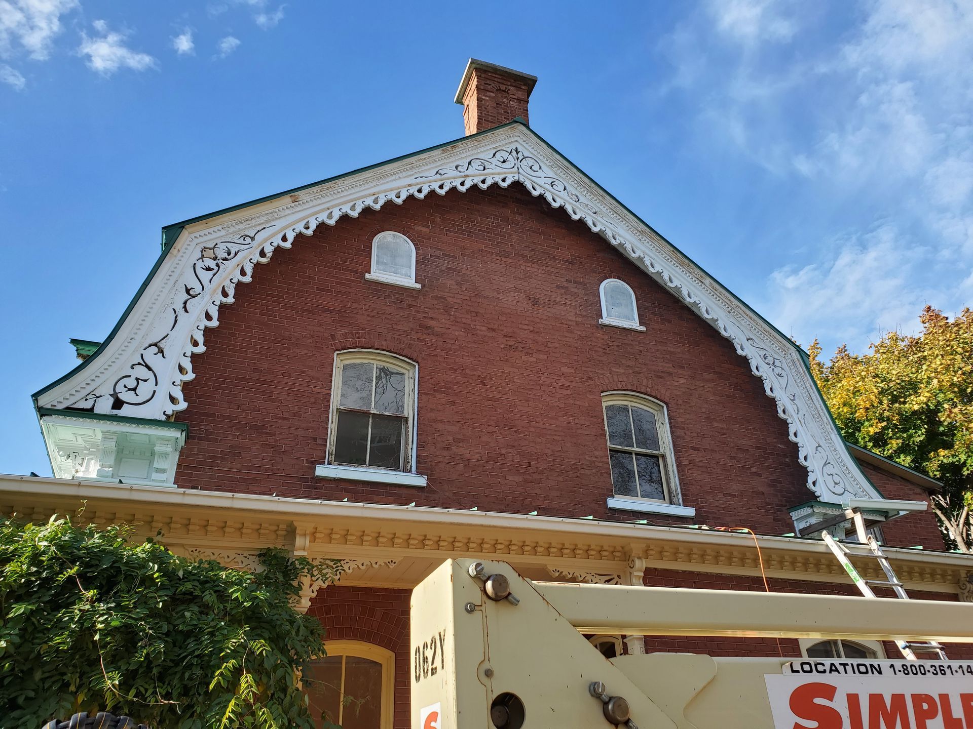 Un grand bâtiment en brique avec un toit en train d'être peint.