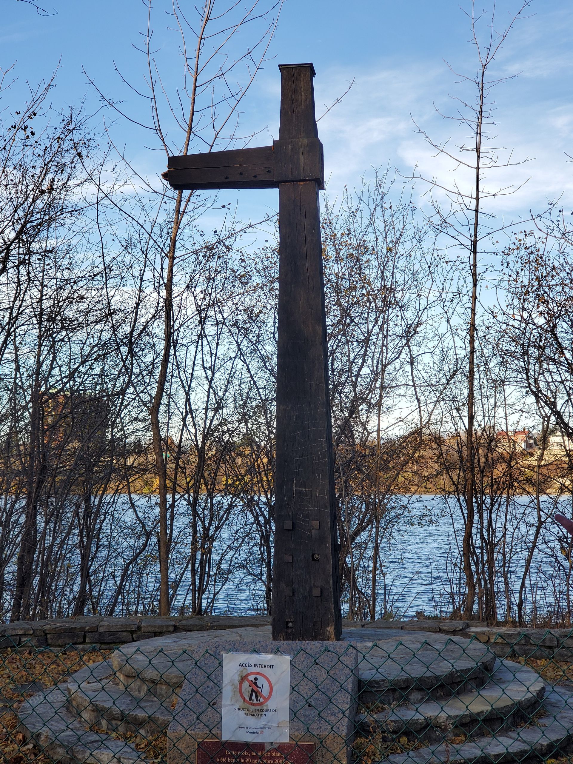 Une grande croix en bois se dresse devant un plan d'eau
