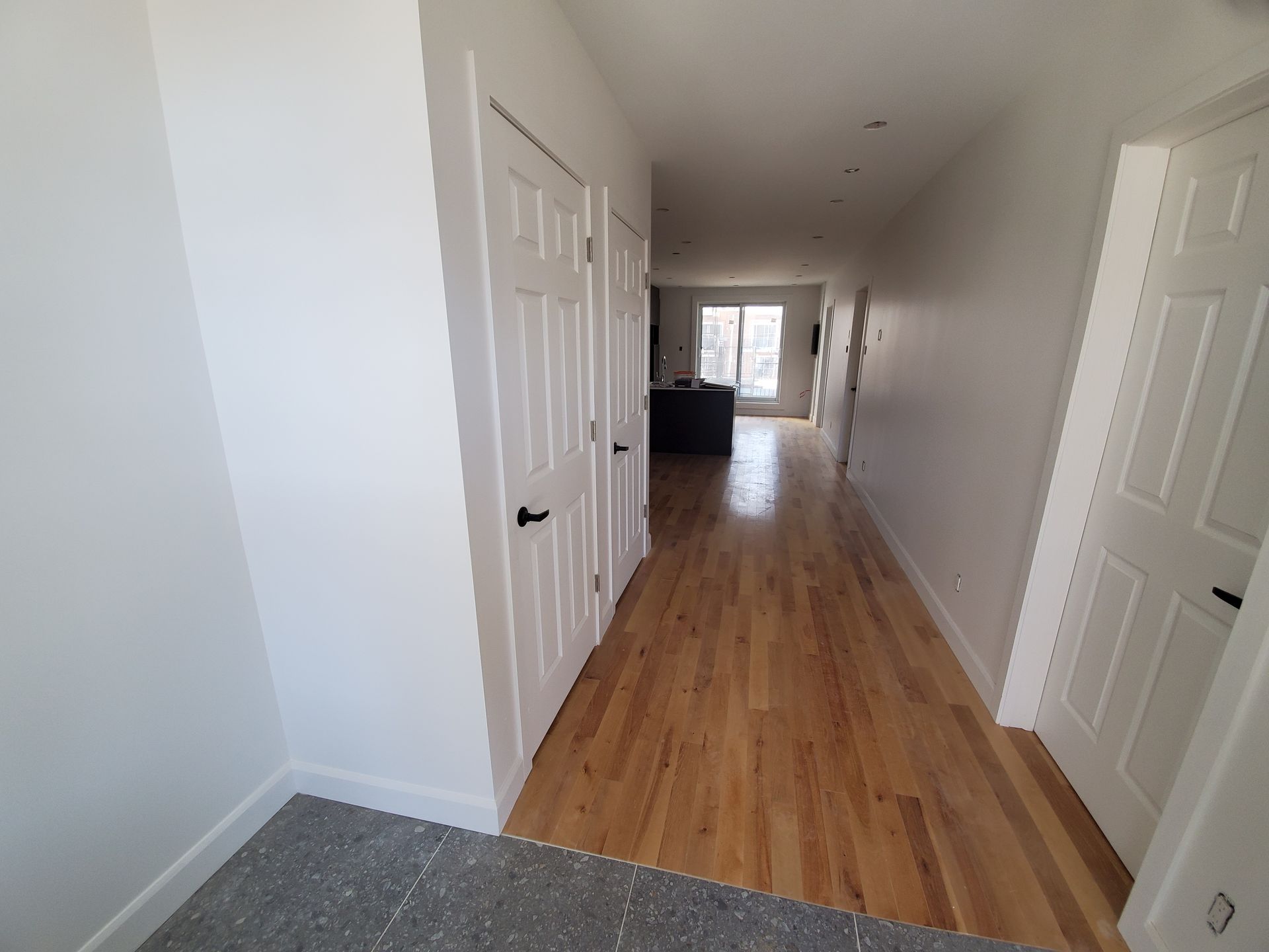 Un long couloir avec parquet et murs blancs