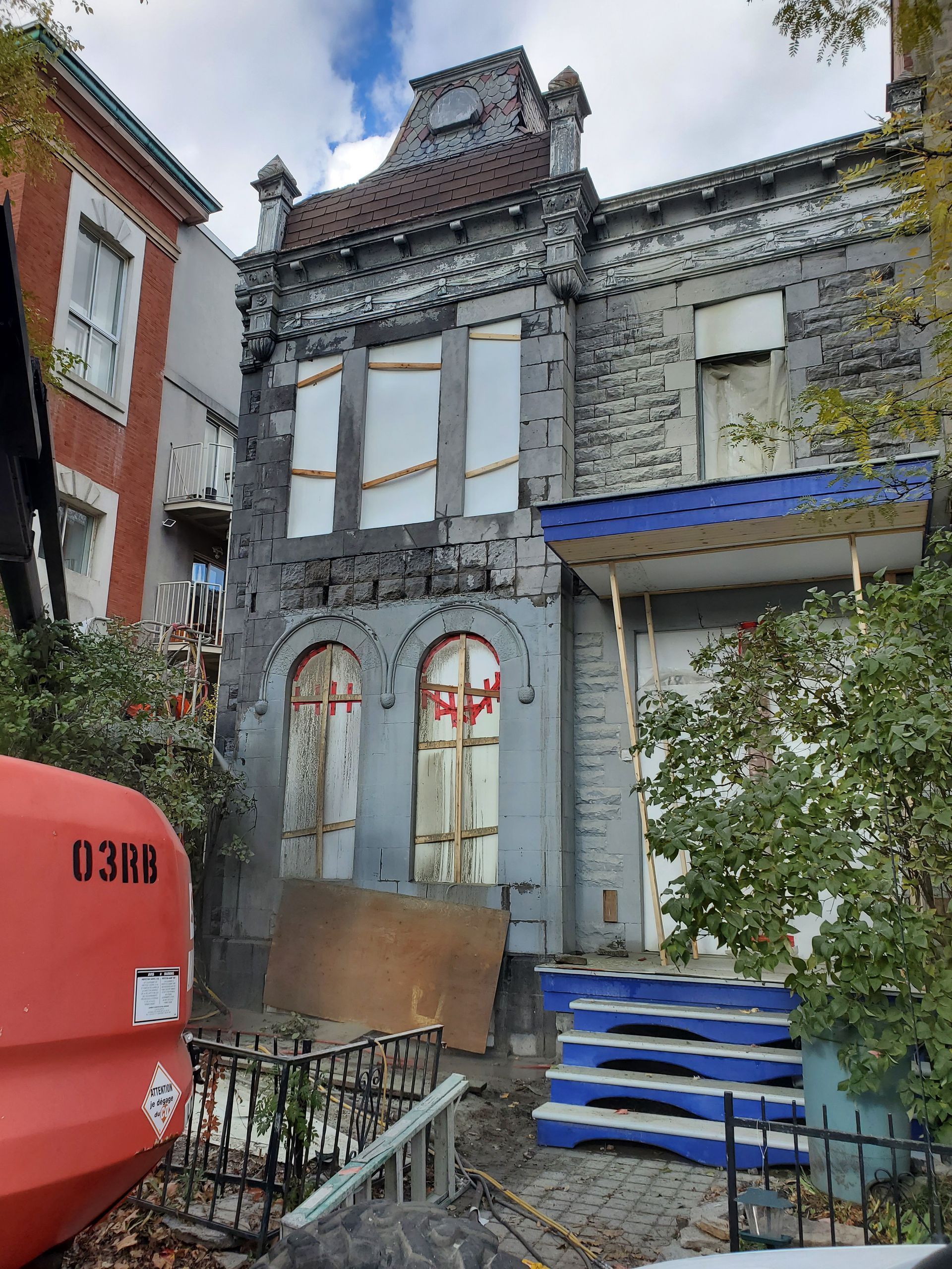 Un grand bâtiment en brique avec un toit bleu est en cours de démolition