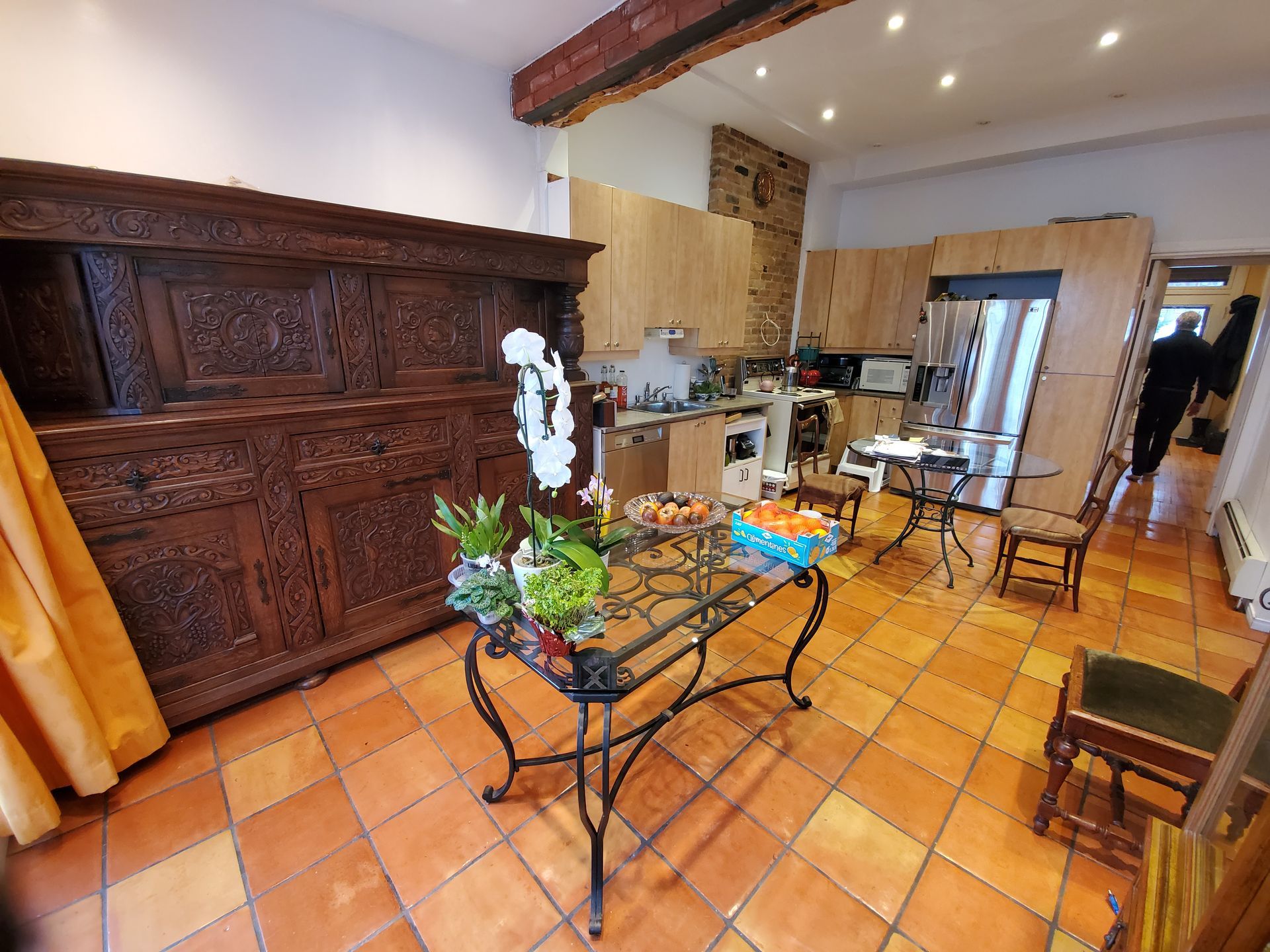 Un salon avec une table et des chaises et une cuisine en arrière plan.