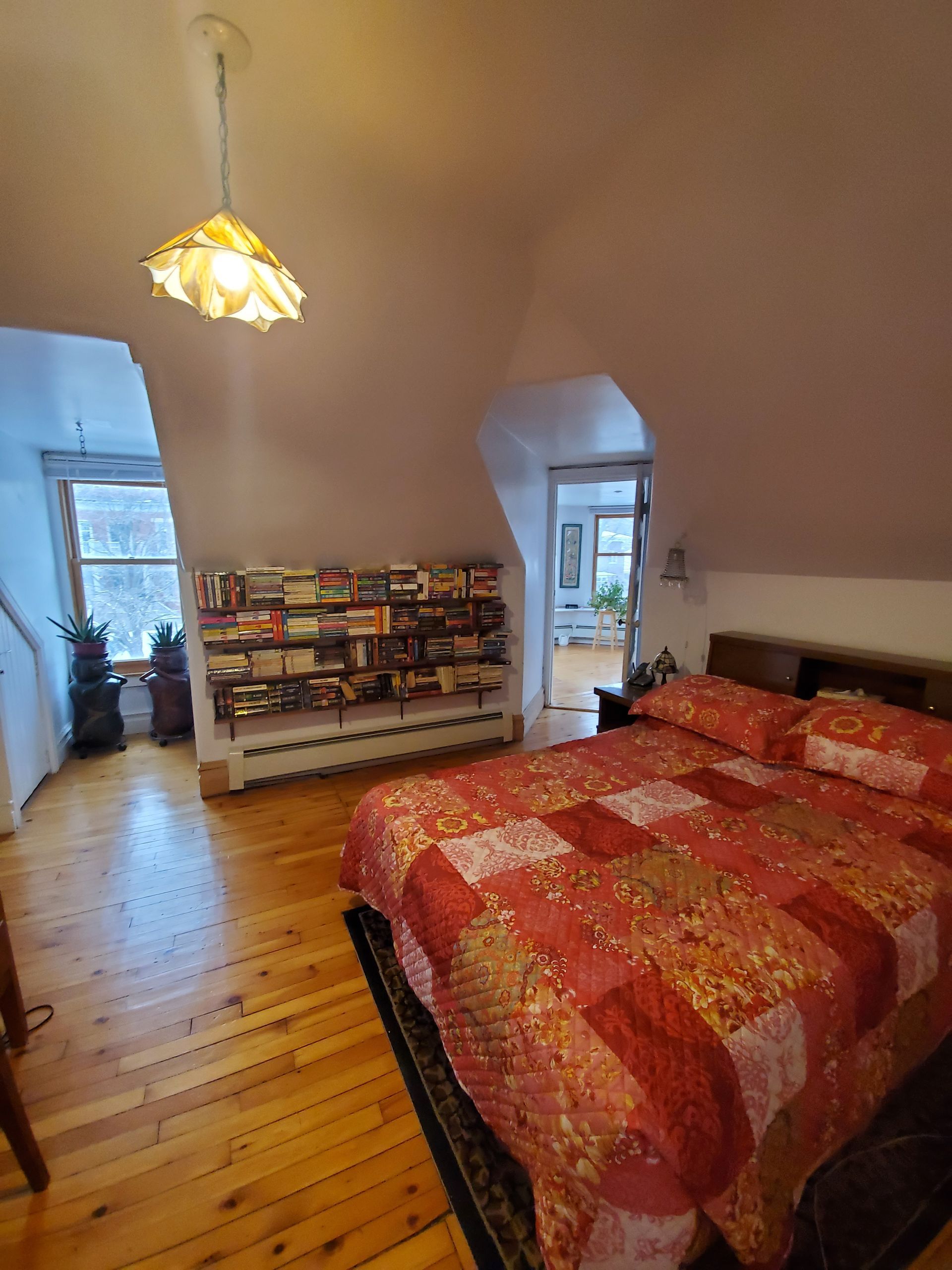 Une chambre avec un grand lit et une bibliothèque remplie de livres.