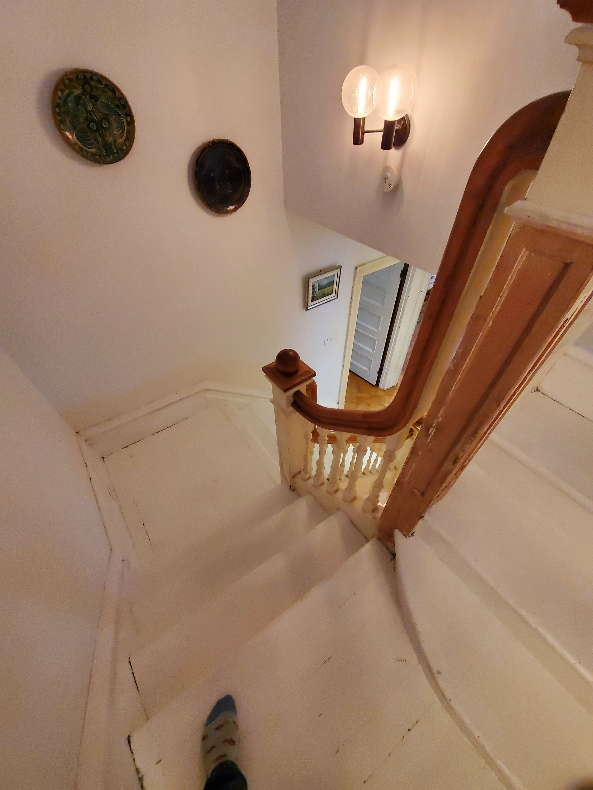 Une personne descend un escalier avec des plaques au mur.