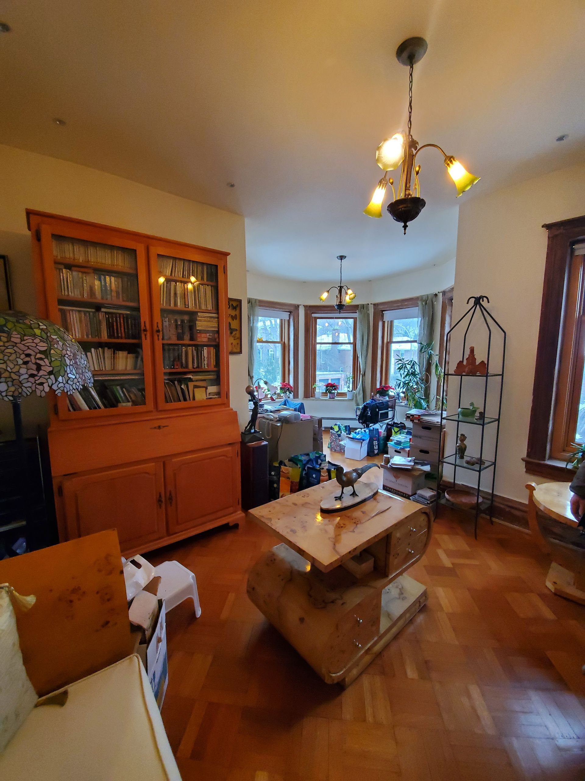 Un salon avec une table basse, un canapé, une bibliothèque et un lustre.