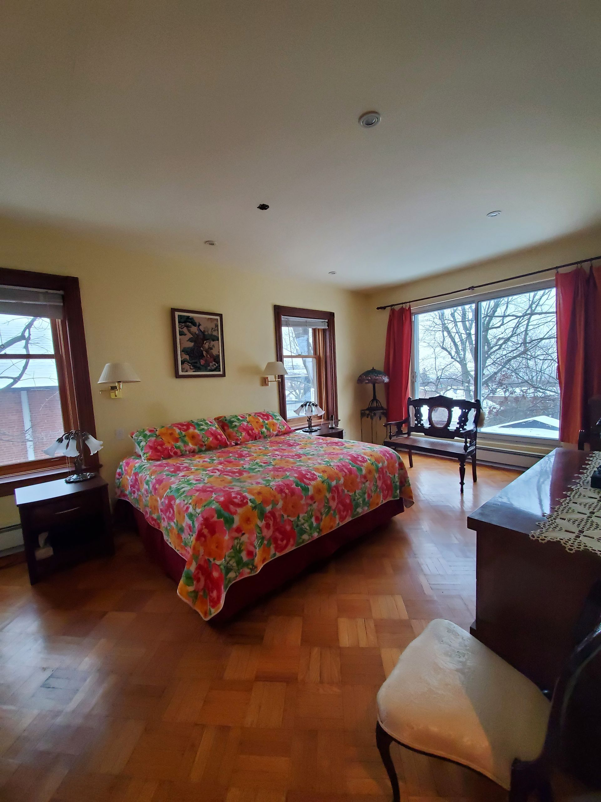 Une chambre avec un grand lit et beaucoup de fenêtres