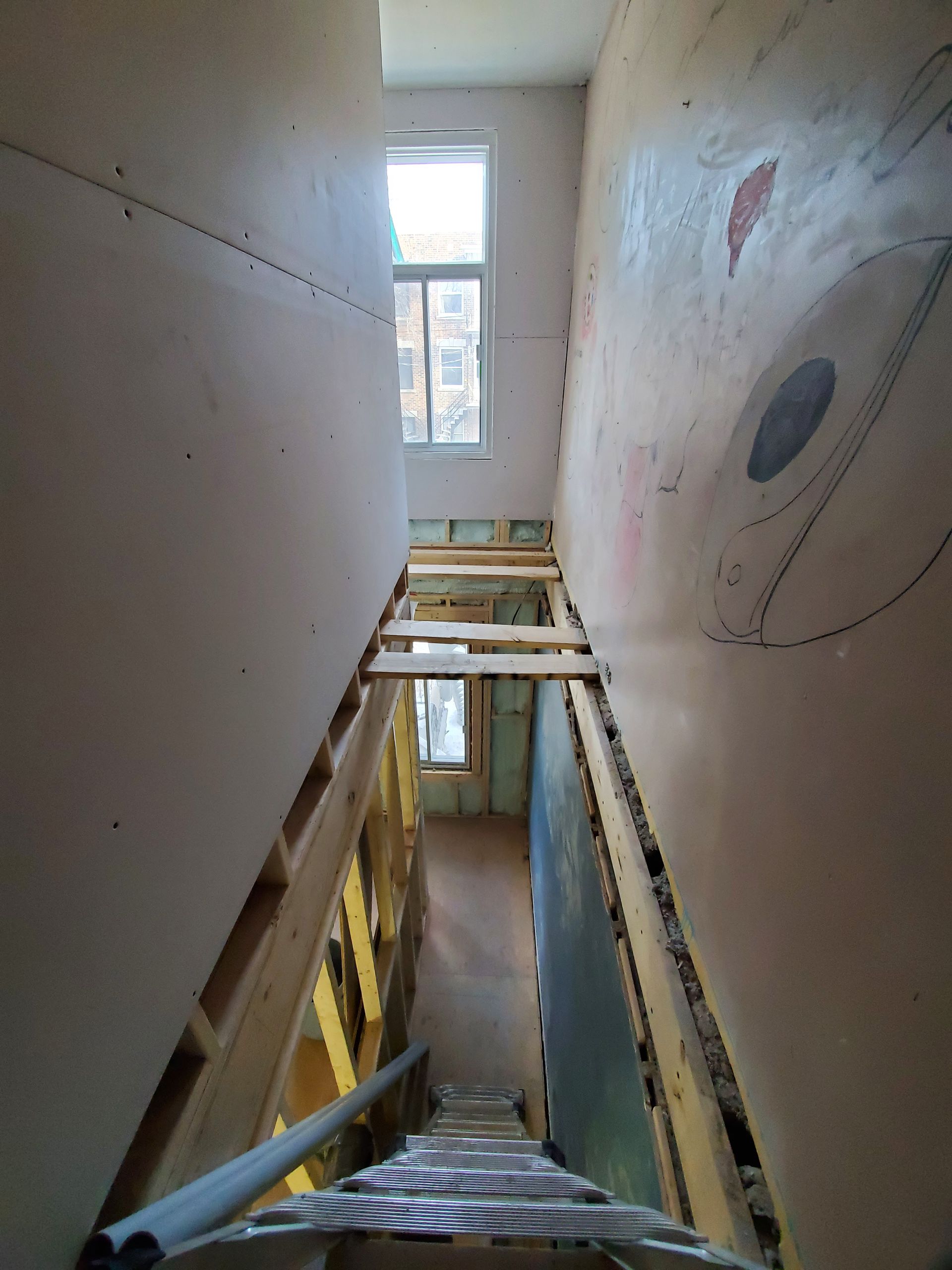 Une échelle monte un escalier dans un immeuble en construction.