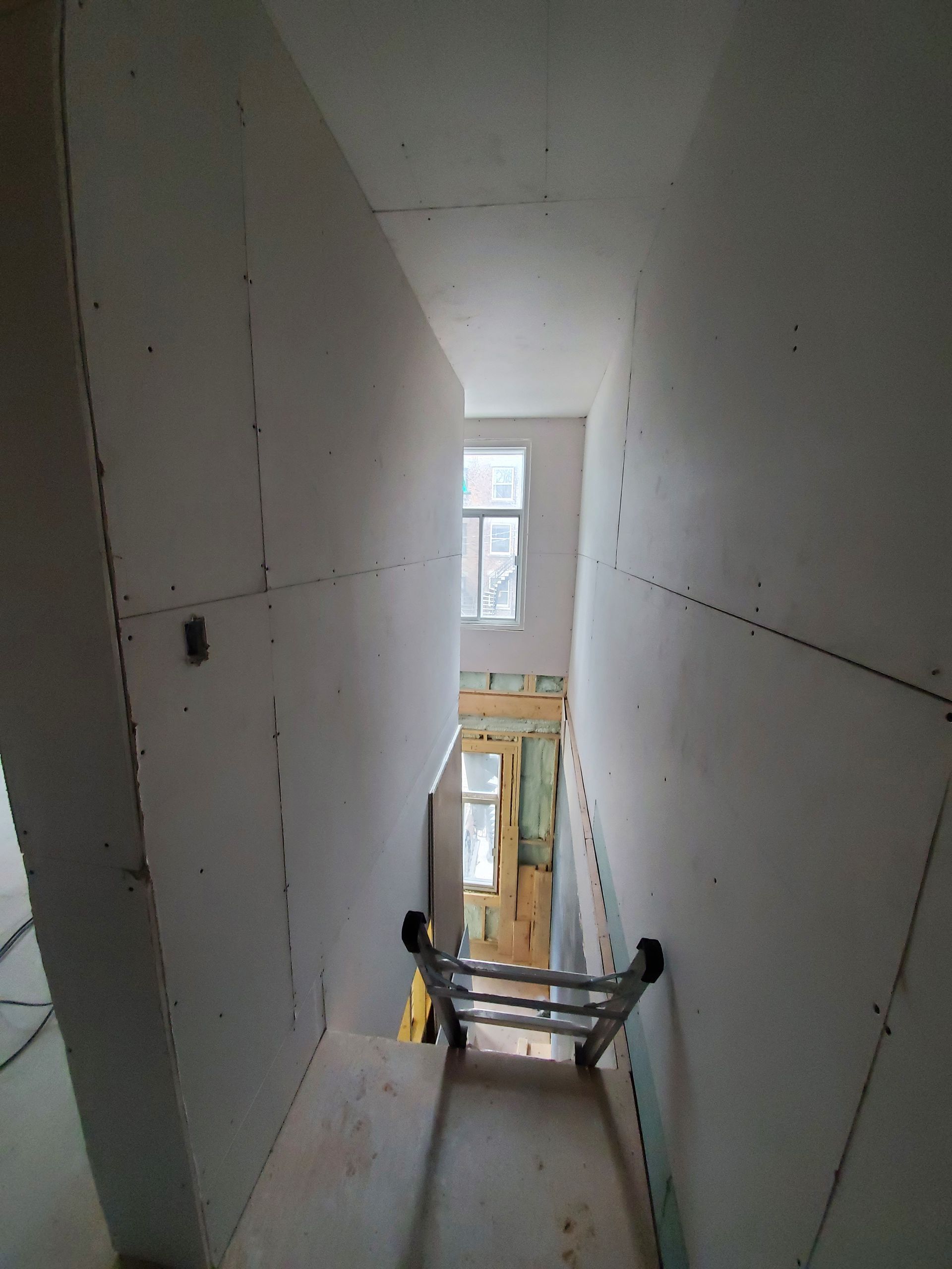 Une échelle monte un escalier dans un immeuble en construction.