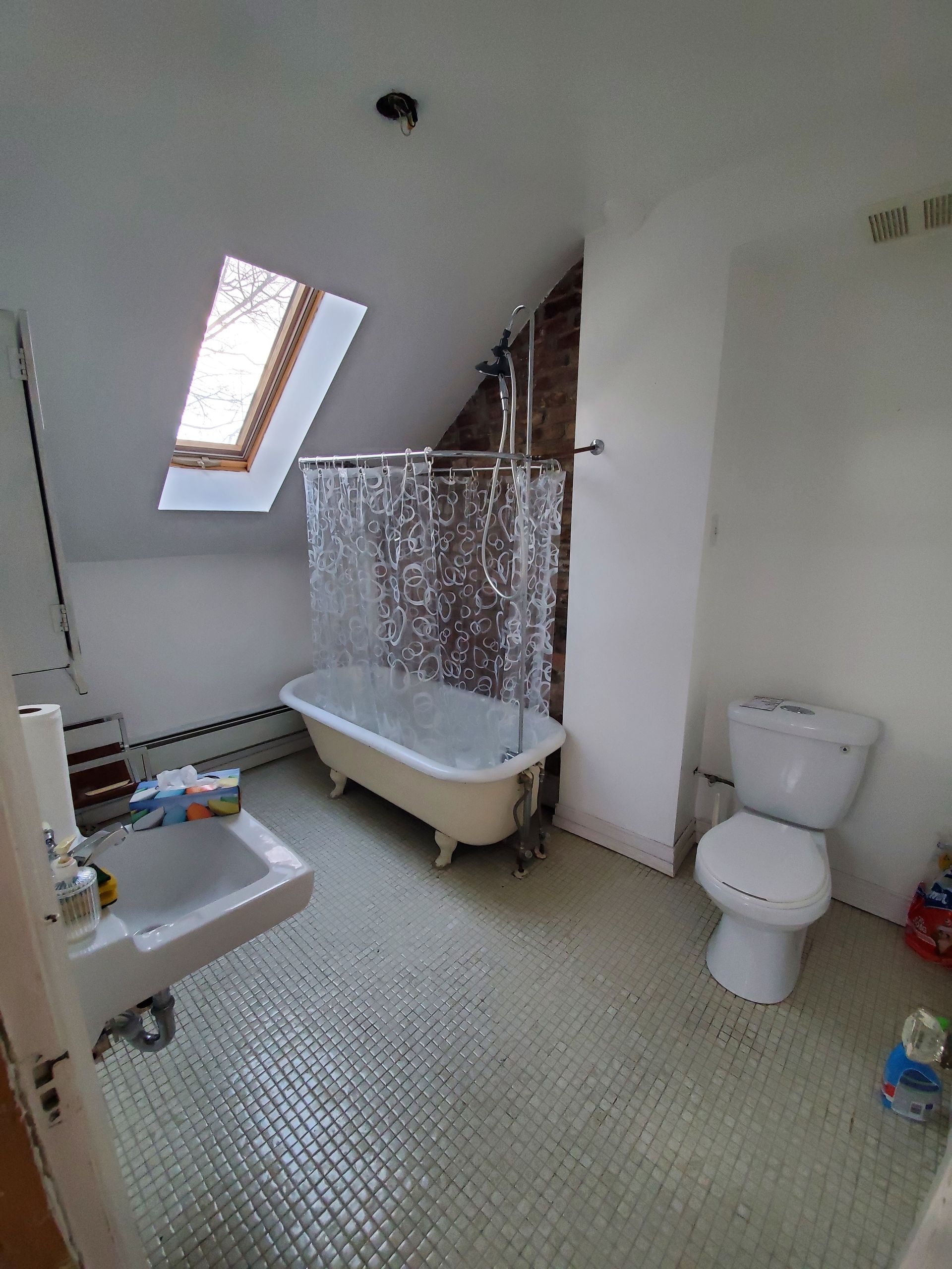 Une salle de bain avec baignoire , WC , lavabo et puits de lumière.