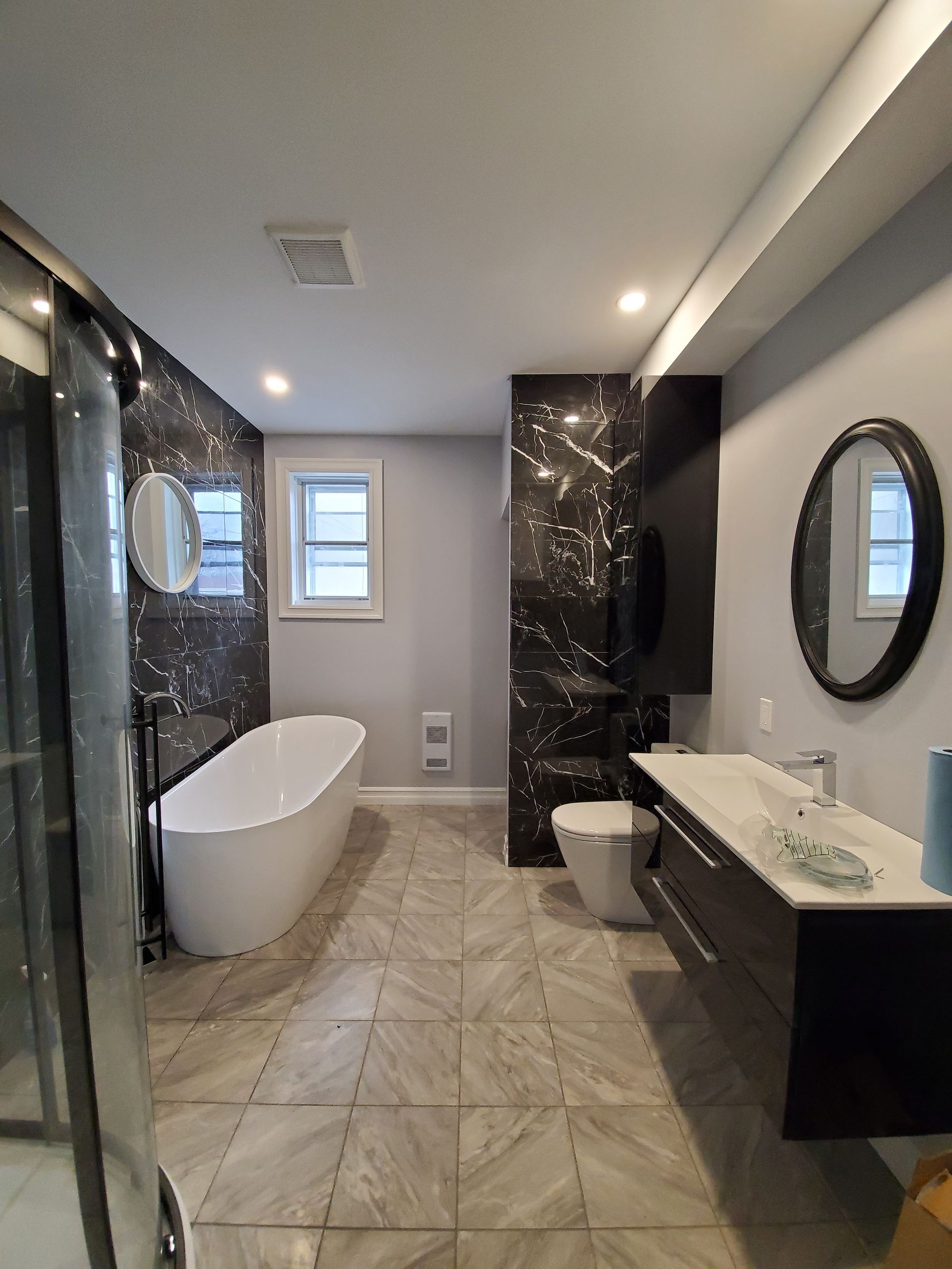 Une salle de bain avec baignoire , WC , lavabo et miroirs.