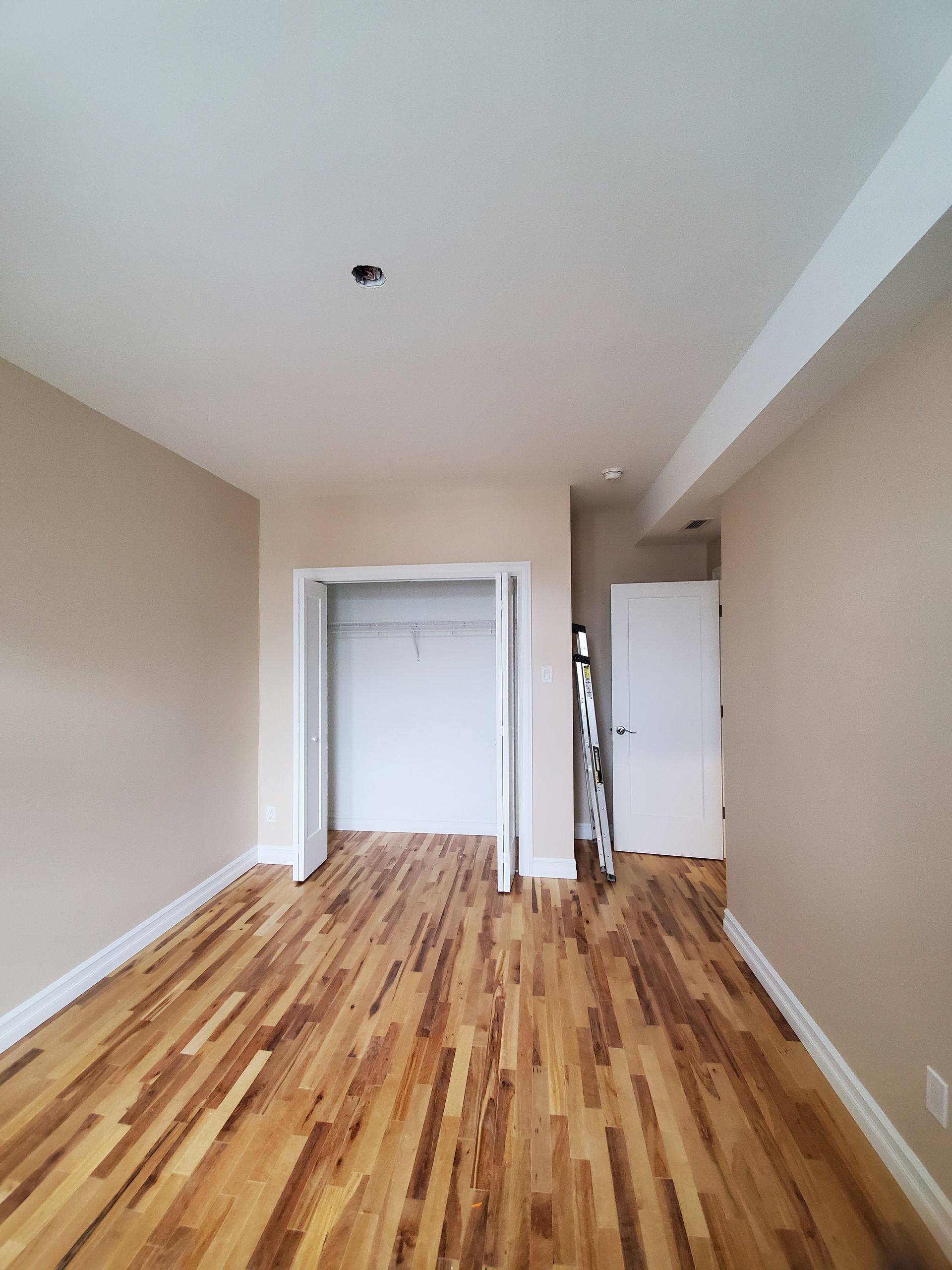 Une chambre vide avec parquet et placard.