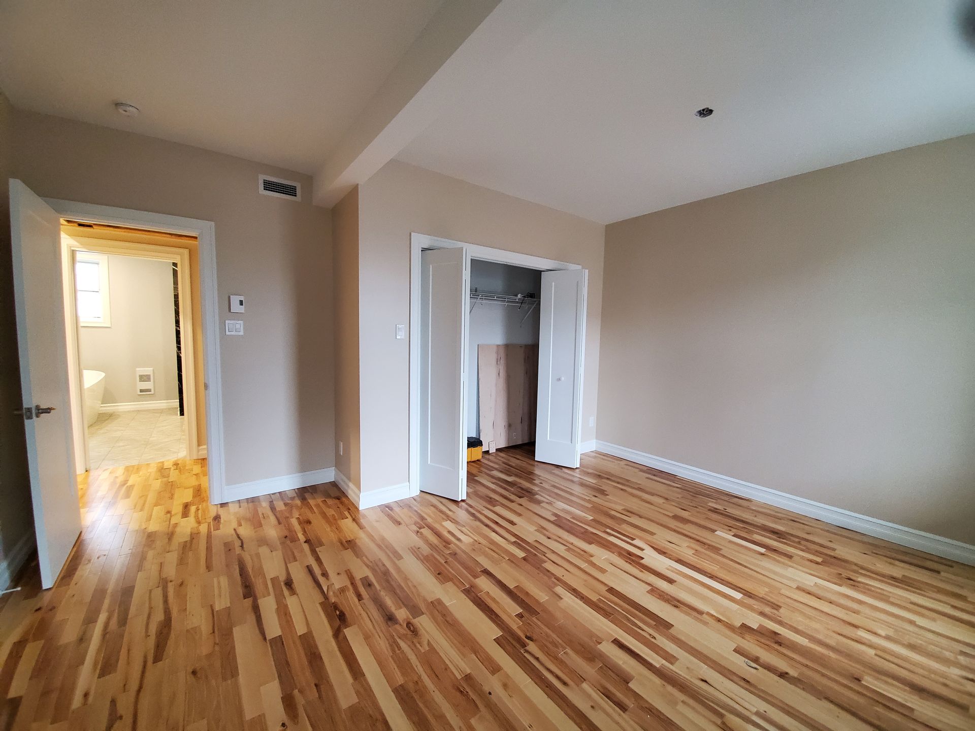 Une grande pièce vide avec parquet et un placard.