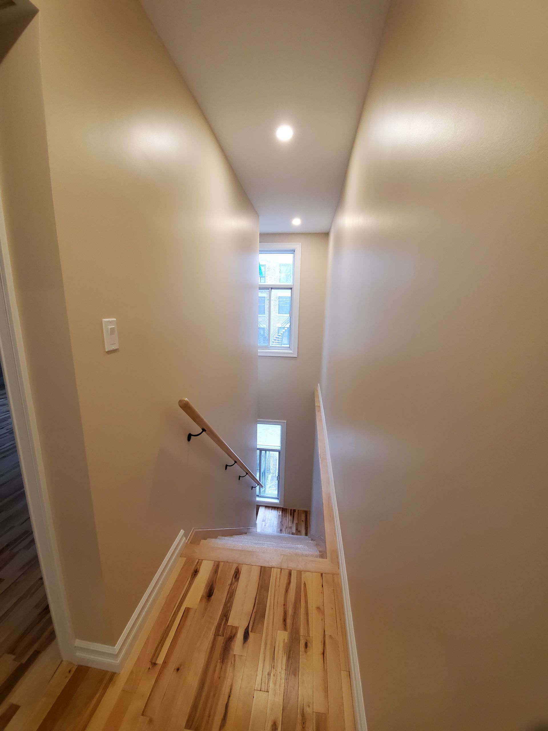 Un couloir avec parquet et escalier menant au deuxième étage.